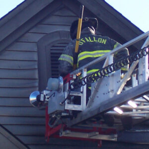 firefighter on ladder inspecting home